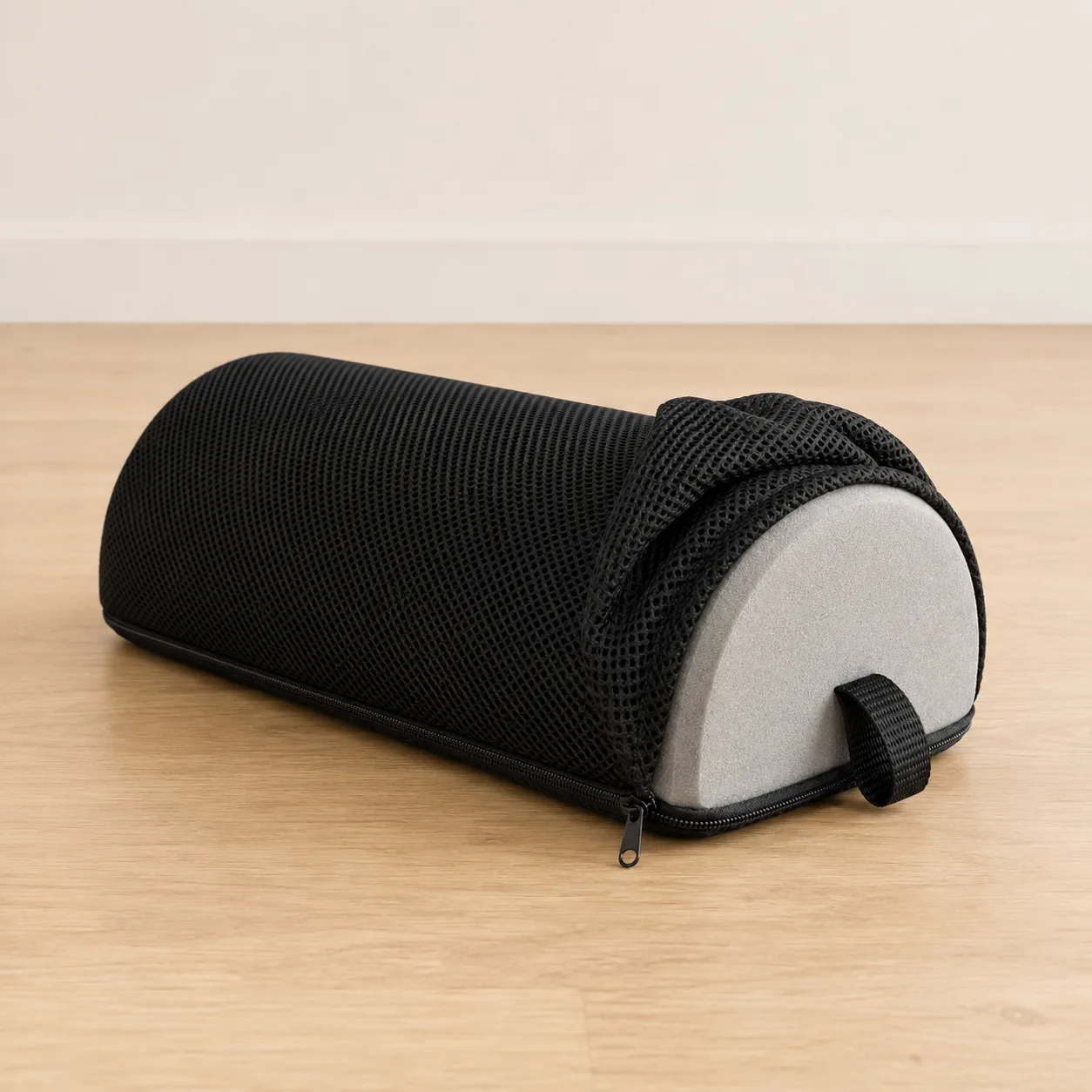 Carton d’expédition ouvert et coussin repose-pied noir posé à côté, sur un parquet clair